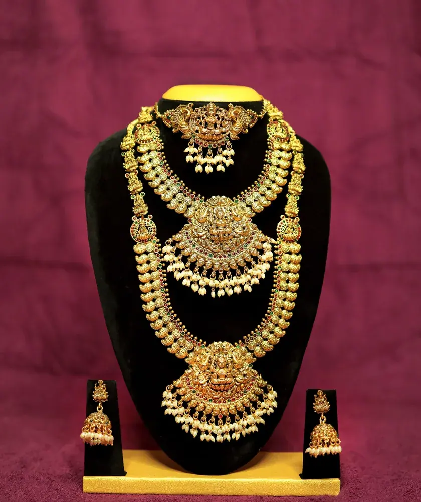 Layered gold bridal necklace set on a display stand
